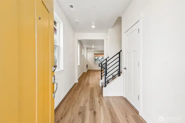 Entry with LVP flooring - black metal stair railing with stained wood handrail.