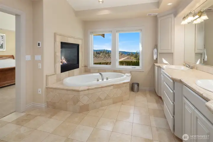 Primary Suite Bath with a jetted soaking tub, gas fireplace, dual sinks and lots of multi-level cabinetry. Heated Travertine floors!
