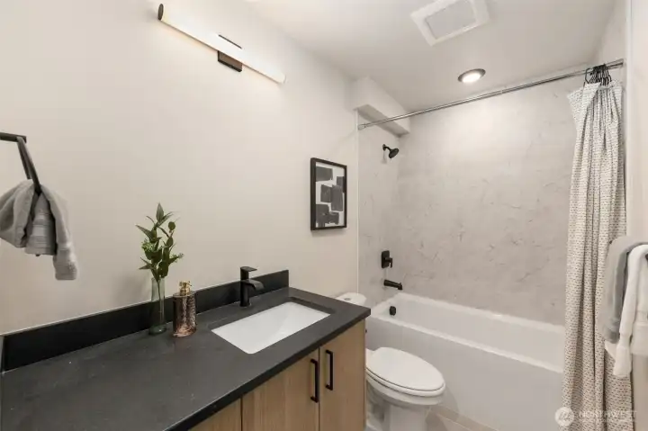 Matte black finishes, designer fixtures, and a floating vanity create a crisp, contemporary feel.