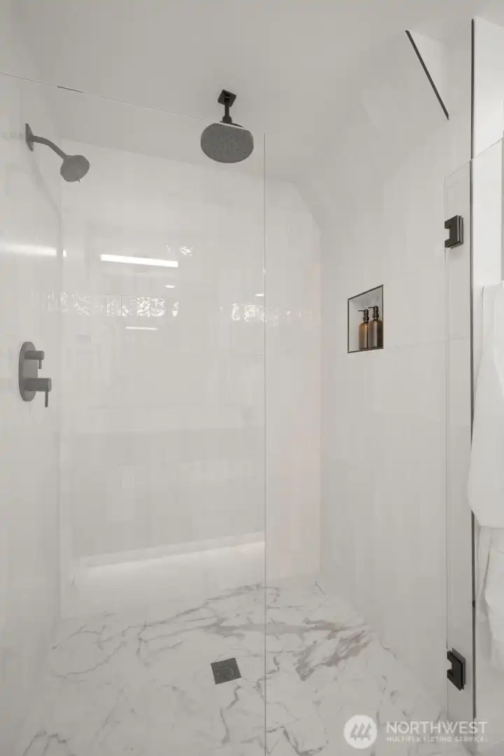 Walk-in glass shower with modern tile surround and rainfall showerhead.