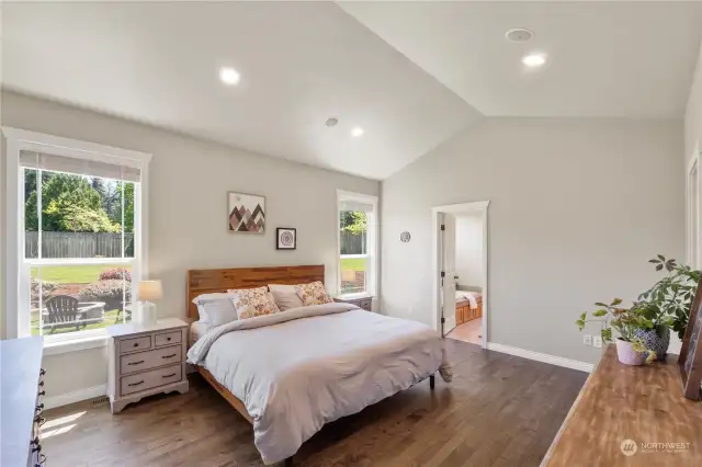 Spacious primary suite overlooking the private back yard with vaulted ceilings, a big walk-in closet and gorgeous hickory flooring