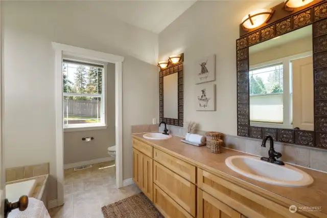 Hickory cabinetry, an expansive counter space with double sinks & decorative mirrors and lighting enhance the attached primary bath