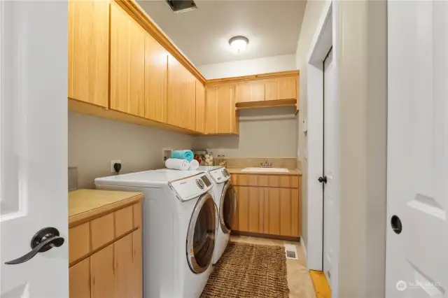 The huge laundry room offers tons of cabinet & separate closet storage plus a utility sink & folding counter. The front load washer and dryer are included.