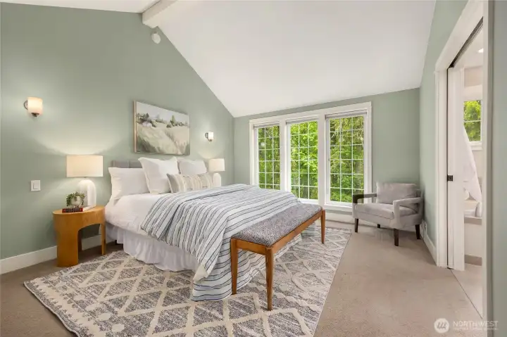 Upstairs, the primary bedroom features vaulted ceilings and large windows.