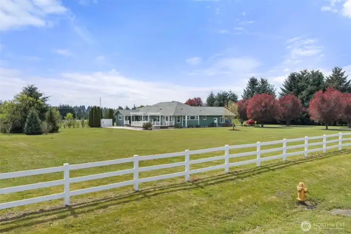 Charming white fence lines the front, creating a warm and inviting entrance