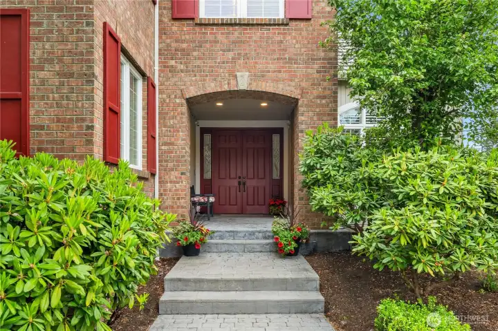 Custom stamped concrete walkway leads to a beautiful arched brick facade and a stately double door entry with two leaded glass sidelights  The large covered porch has plenty of room for a bench and decorative plants.