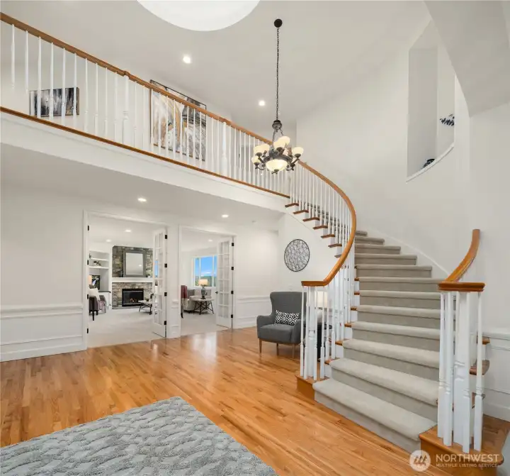 The sweeping staircase, soaring ceilings, and open area overlooking entry are breathtaking.  The double set of tall French doors leads guests to the entertainment-sized family room.