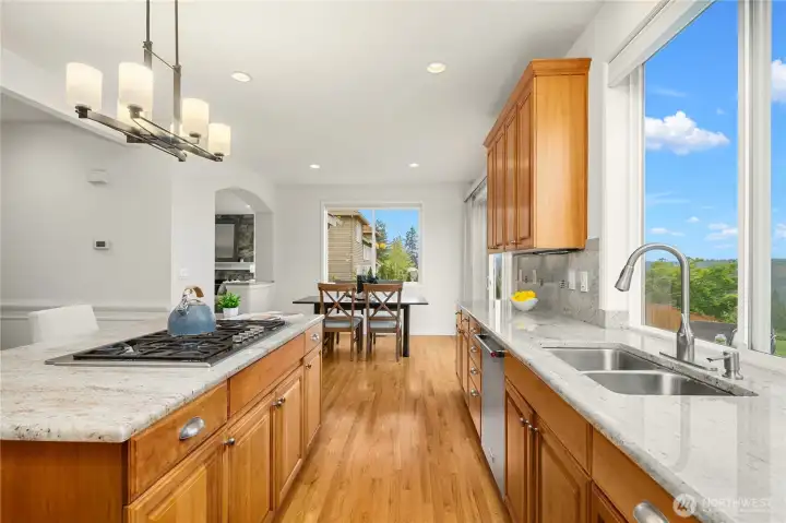 This view from the kitchen showcases the five-burner Thermador cooktop, gleaming stainless double sink, view from the kitchen window, and the generous kitchen eating area ideal for watching sunrises over the mountains.
