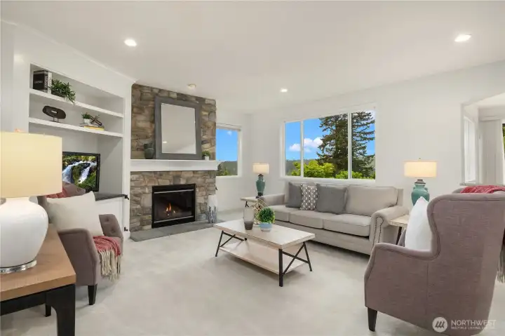 Spacious family room with custom stone-faced gas fireplace features built in display shelves and a granite counter ready for a large screen TV.  Windows flood this special gathering area with light and Cascade mountain views.
