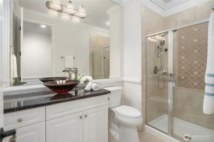 Next to the office, but accessed from the hallway, is this elegant 3/4 bath with granite counter, elegant vessel sink, new comfort height Kohler toilet, and custom ceramic tiled step-in shower, perfect for family or guests.