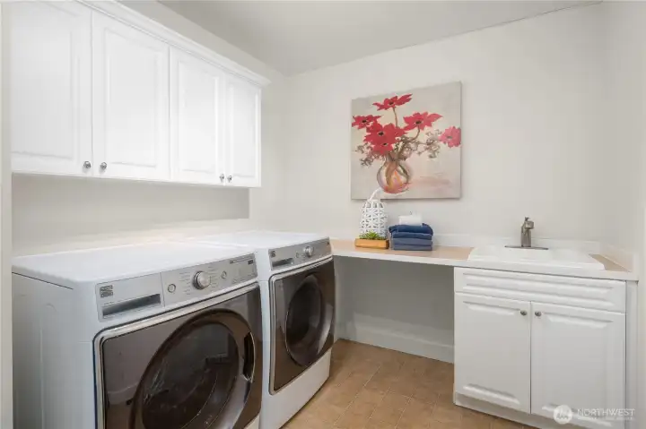 Main floor generous utility room is conveniently located near the garage and has plenty of storage cabinets, a deep utility sink, and folding counter.  Large capacity front loading washer and dryer are included in sale.
