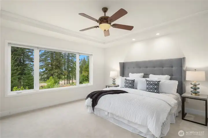 The oversized primary bedroom sits in its own wing at the top of the stairs, with captivating views of the green space and Cascade mountains.  The ceiling fan adds comfort and ambiance to this lovely private retreat.