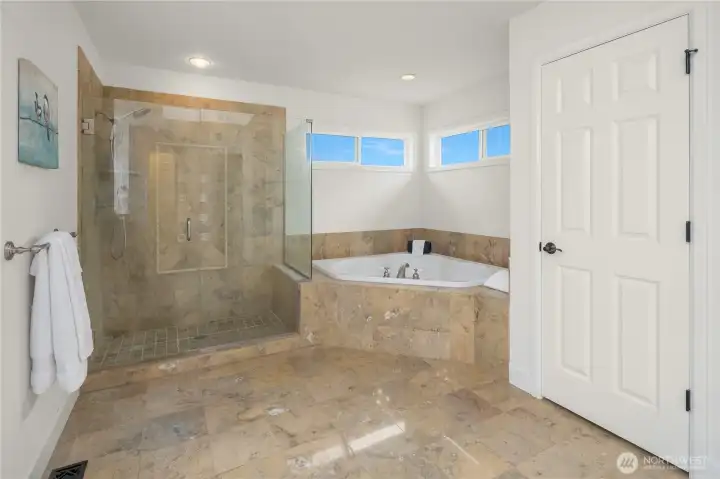Glistening marble tile floors lead to the custom travertine tiled shower with frameless glass enclosure and deep soaking tub.  Linen closet to the right is convenient for towel and bedding storage.  So spa-like and beautiful...
