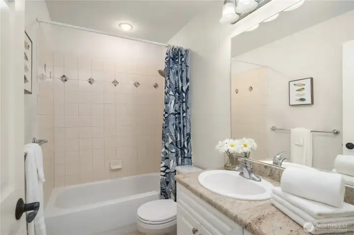 Full hall bath has a beautiful tiled bathtub surround and a vanity with a granite counter. Floor has ceramic tile.