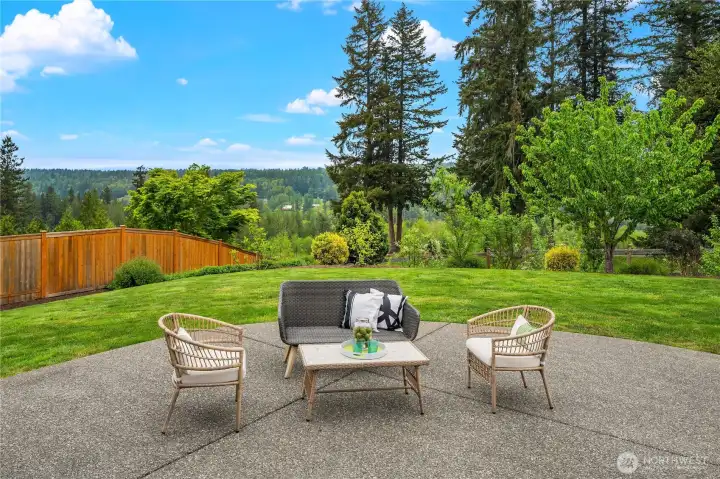 Here's a huge patio that's great for entertaining!  Cascade mountain and valley views create privacy with a level backyard and green space behind the property. The backyard is fully fenced, with side cedar fences new in 2025.