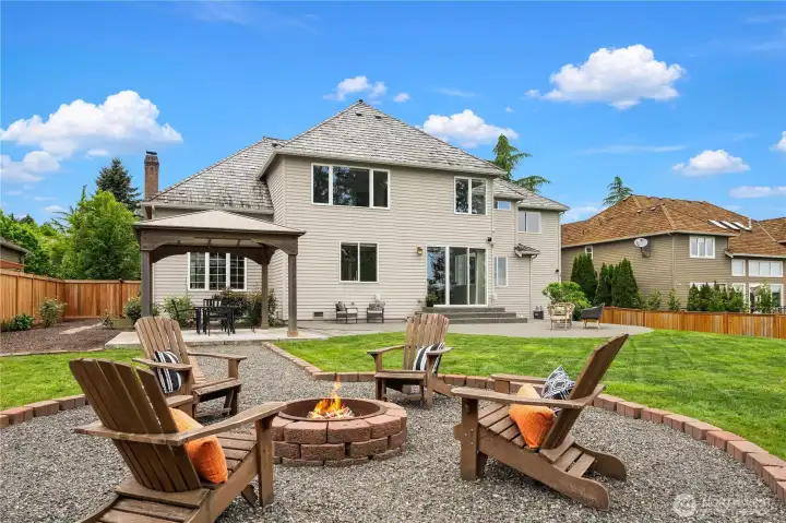 View from the expansive custom fire pit shows how entertaining areas flow together.  The large adjacent grassy area is perfect for playing active games.
