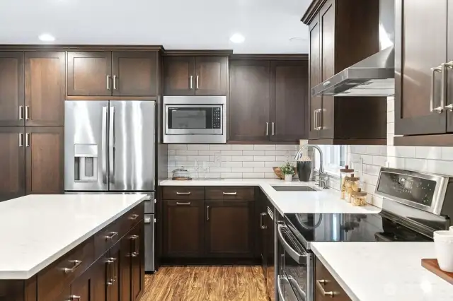 Stainless steel appliances include a french door refrigerator, double oven, exhaust hood and built in microwave.