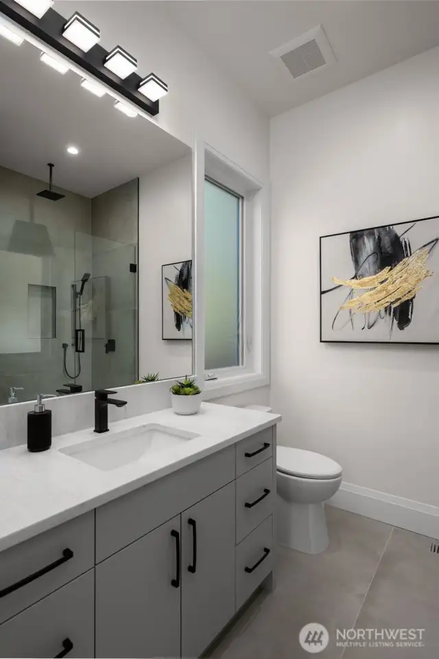 Main floor 3/4 bath with custom tile shower and frameless shower glass.
