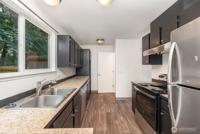 The kitchen features dark toned cabinetry, stainless steel appliances and ample counter space.