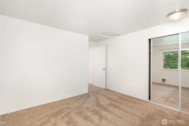 Guest bedroom also features sizable closet with mirror closet door.
