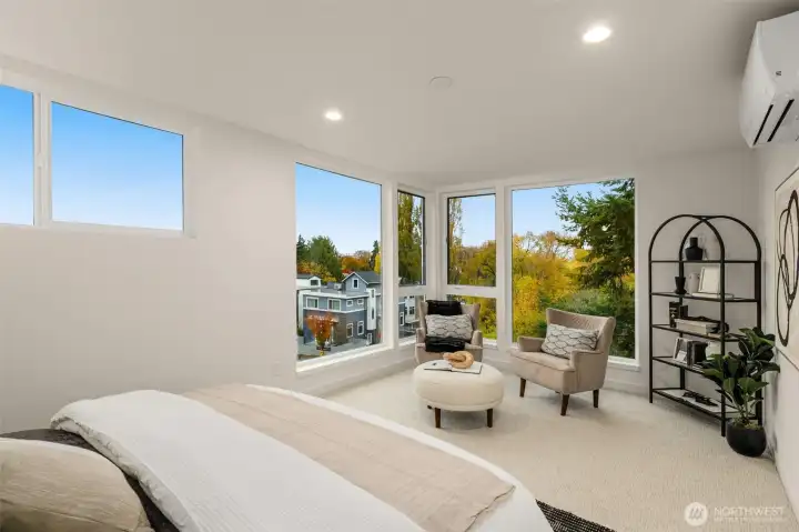 Primary suite boasts cornered walls of windows, flooding the room with natural beauty while providing an excellent view
