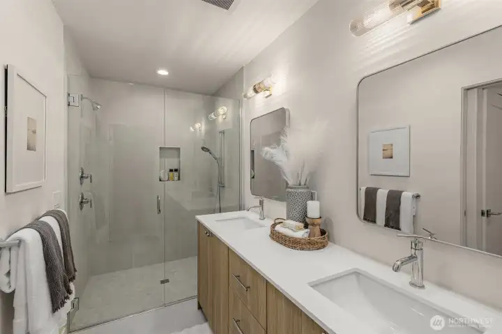 The primary bath continues the luxurious feel, wood grain cabinetry, quartz counters, full tile shower surround, & glass door entry