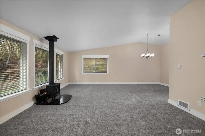 Enter to find your large vaulted living space directly to left of entryway. Space is filled with natural light with abundance of windows, new carpeting, and fresh paint make the space feel new. A wood burning fireplace cozies up the space creating a warm ambience and providing an additional great heat source to the home.
