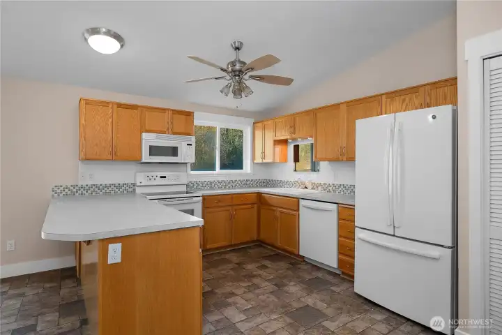 Close up view of open-concept kitchen with large peninsula and plenty of entertaining and counter space. Plenty of storage cabinetry and natural light. All appliances stay with home.