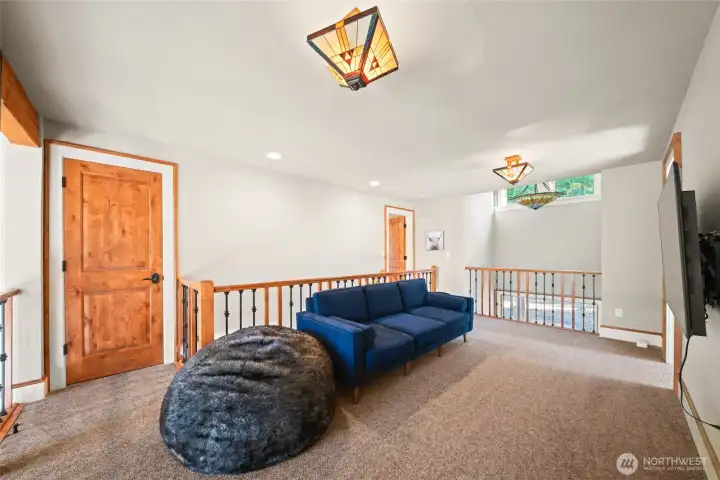 Upper loft space, open to the living room below. Lovely stained glass fixtures and a view of the impressive stone fireplace.