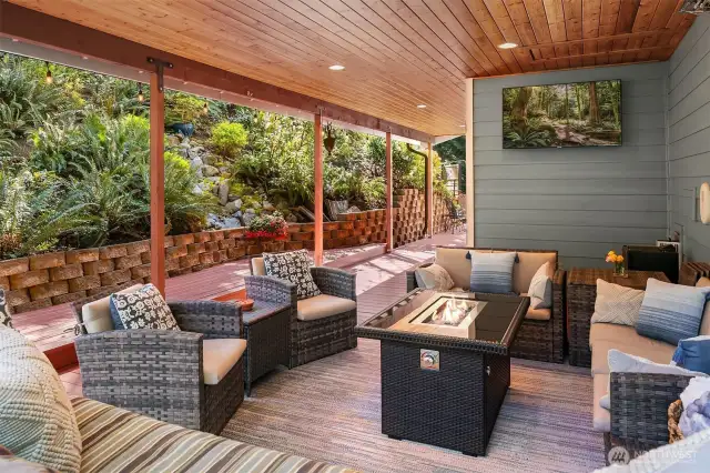 The wrap-around deck is flanked by lush, native greenery.