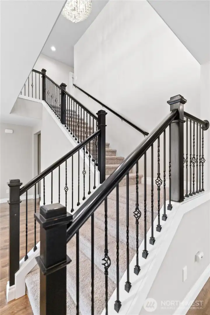 Elegant Stairwell with Wrought Iron Railing and Stunning Chandelier at the Top.