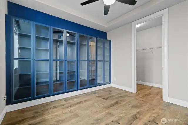 Main Level Bedroom or Office Space Features Beautiful Glass Cabinetry, Ceiling Fan and a Walk-in Closet.
