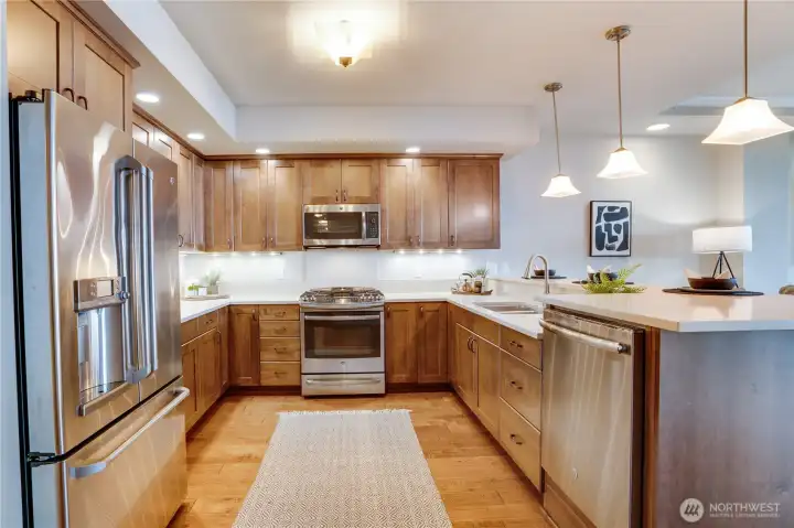 The bright, gourmet kitchen showcases sleek quartz countertops, undercounter lighting, abundant storage, and elegant cabinetry—designed to inspire both everyday living and elevated entertaining.