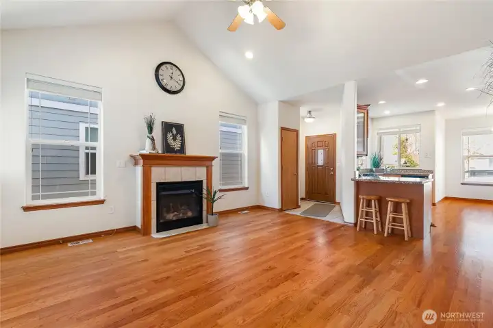 This large living room with vaulted ceilings and cozy gas fireplace captures the expansive living area opening up to the kitchen and dining area.