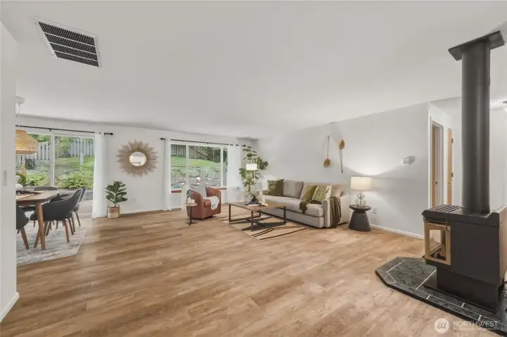 Main living space with tons of windows showing terraced back yard.  Newer vinyl planked flooring throughout main living areas and bedrooms of home.