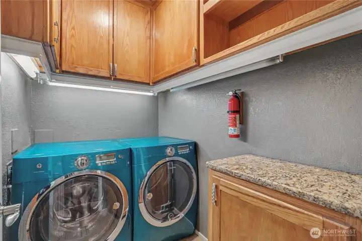 Nice utility room with folding area, cabinets galore and included washer and dryer.