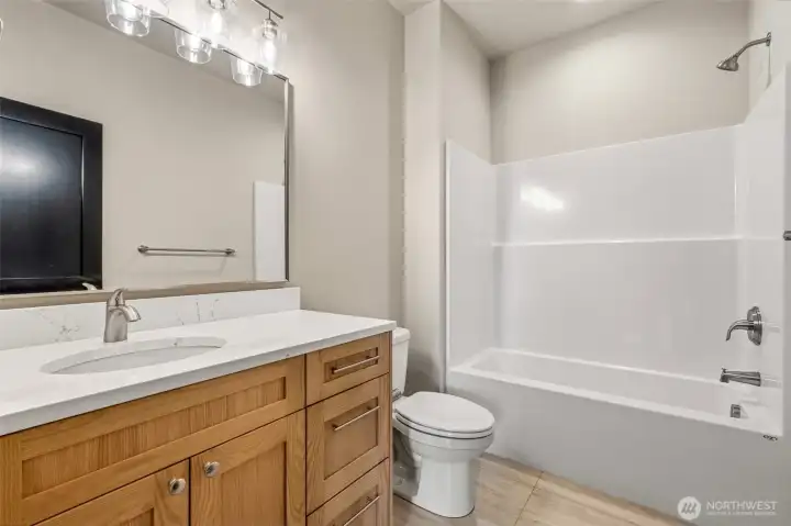 Full bathroom complete with a shower, tub, mirror lighting, storage, and elegant design.