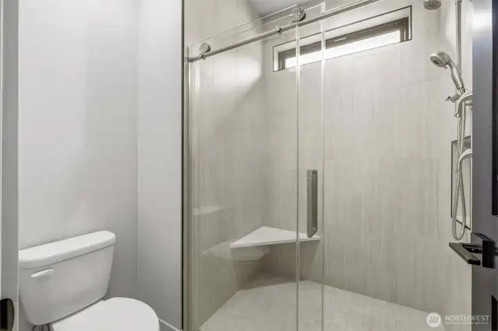 Toilet and spacious shower with door for privacy.
