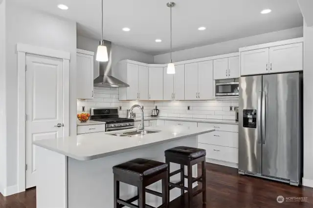 Another view of this stunning kitchen with quartz counters, large white tiles and stainless steel appliances (included and in perfect condition...like the rest of the home). There is also a large pantry to the left of the range.