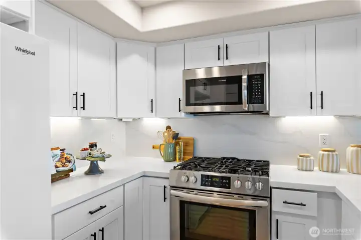 The kitchen has been updated with new quartz countertops, new shaker cabinets, new under cabinet lighting, new overhead LED lighting, and a new dishwasher.