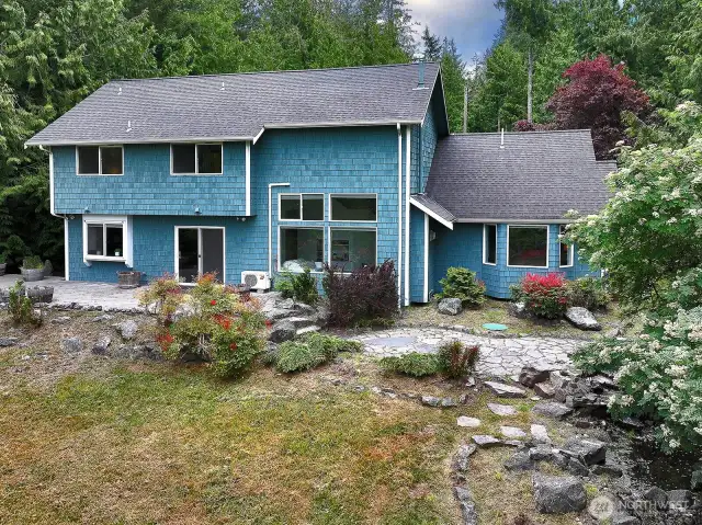 This is the west side of your home. The windows on the far right belong to the Primary Suite. The large windows to the right of the sliding doors is your cathedral ceiling family room. Sliding doors and windows to the left are your kitchen and dining area. Above windows are to each of the upper level bedrooms.