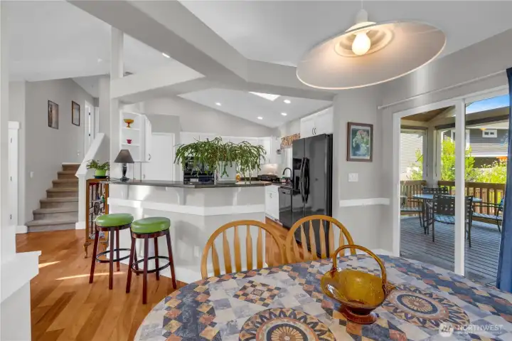 Open and inviting, this space features a bright dining area with sliding doors to the covered deck and a well-designed kitchen with granite counters, bar seating, and ample cabinetry—perfect for everyday living and entertaining.