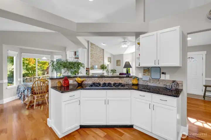 Stylish open-concept kitchen with granite countertops, white cabinetry, and a gas cooktop. Overlooks the bright dining area and living room, creating a perfect flow for entertaining and everyday living.