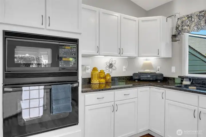 Bright and functional kitchen with granite countertops, white cabinetry, and built-in appliances. Ample counter space and under-cabinet lighting make it both stylish and practical for everyday cooking.
