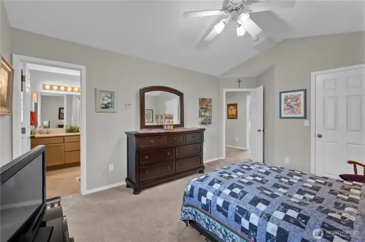 A comfortable and airy primary suite with vaulted ceilings, neutral tones, and an en suite bath. Warm natural light and classic finishes make this space both relaxing and inviting.