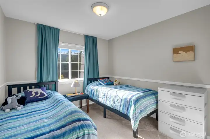 Cheerful room with soft natural light, neutral walls, and a large window overlooking the backyard—perfect for guests or a cozy children’s space.
