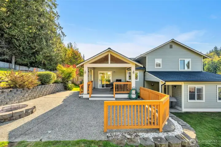 Charming and well-maintained, the back of the home features a spacious covered deck, extended patio, and built-in fire pit. Surrounded by mature landscaping and trees, it’s perfect for relaxing or entertaining outdoors.