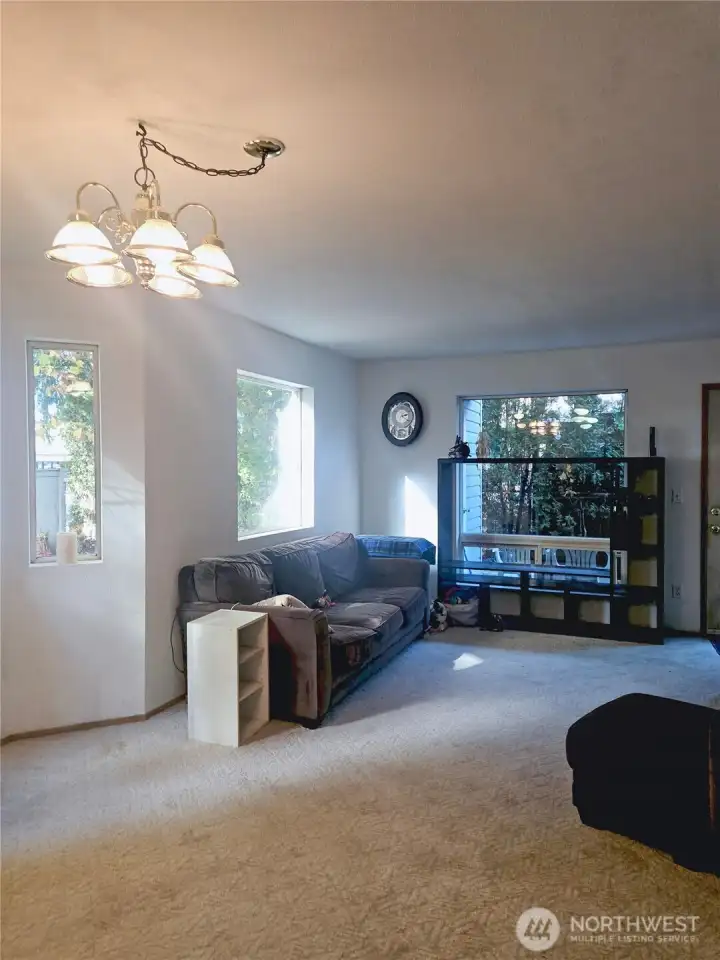 The living room offers a comfortable, light-filled space with large windows that bring in the surrounding greenery. The open layout provides plenty of room for relaxing or entertaining, creating a cozy centerpiece for everyday living.