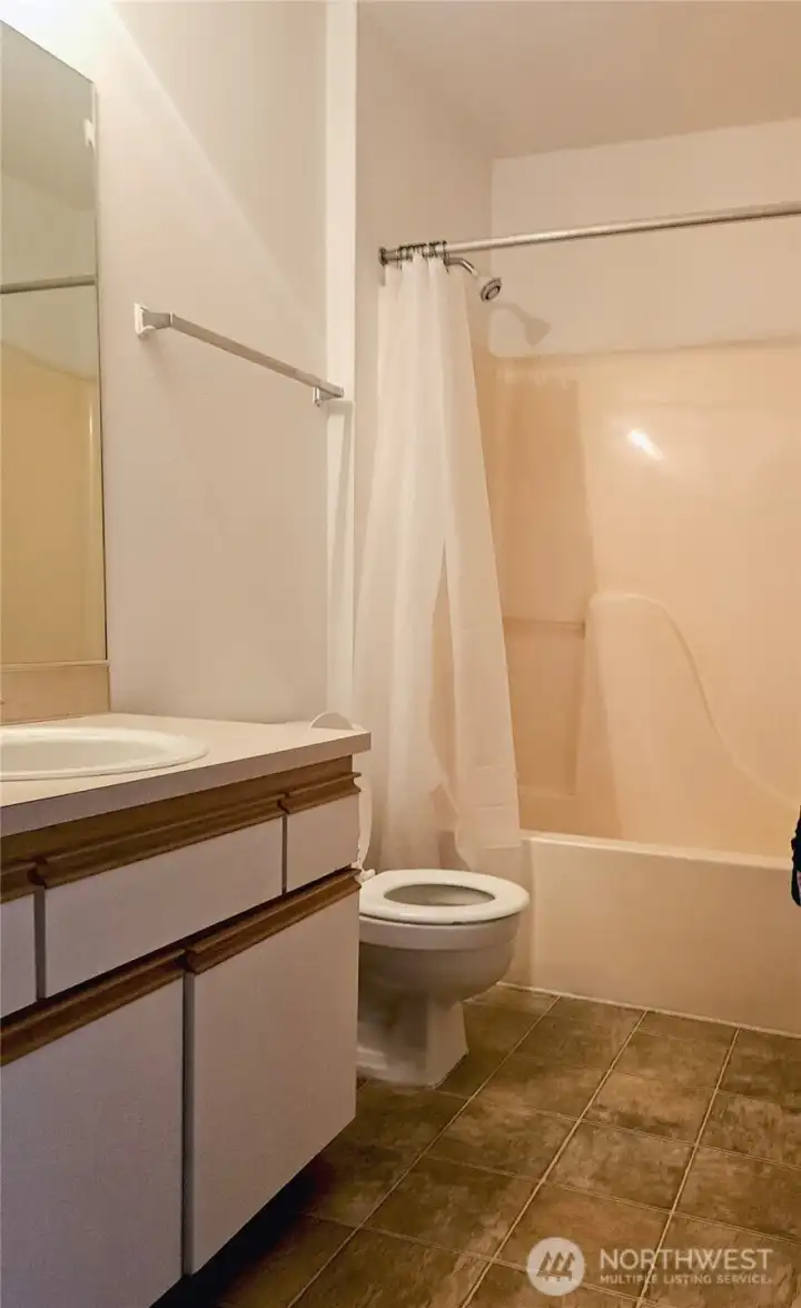The main bathroom features a full tub and shower, a spacious vanity, and neutral finishes throughout. Its practical layout offers plenty of room for daily routines and guest use.