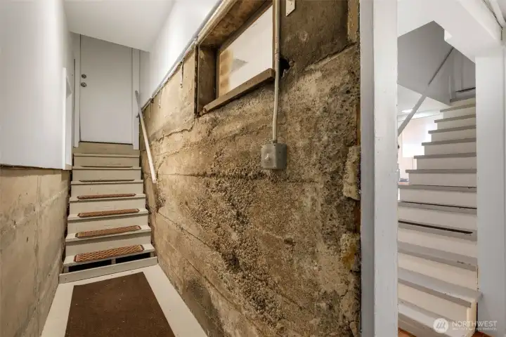 Hallway entering the lower MIL from the south side exterior door- the furnace is at the end of the hall and there is a large crawl space that can fit storage.